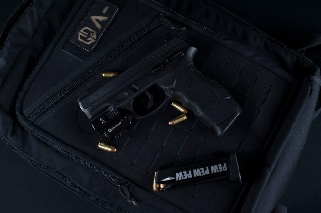 A black handgun and bullets on a tactical backpack, ideal for security and defense concepts.