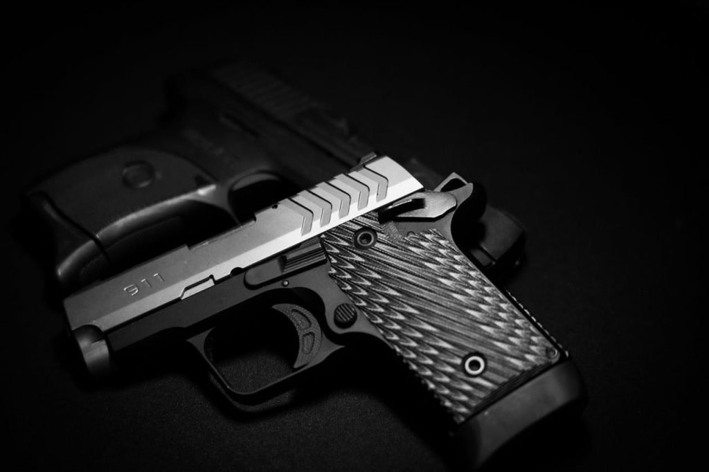 A detailed grayscale shot of a black and silver pistol on a dark surface.