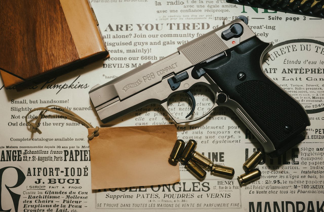 A Walther P99 Compact pistol displayed with bullets and a wooden box on vintage paper.